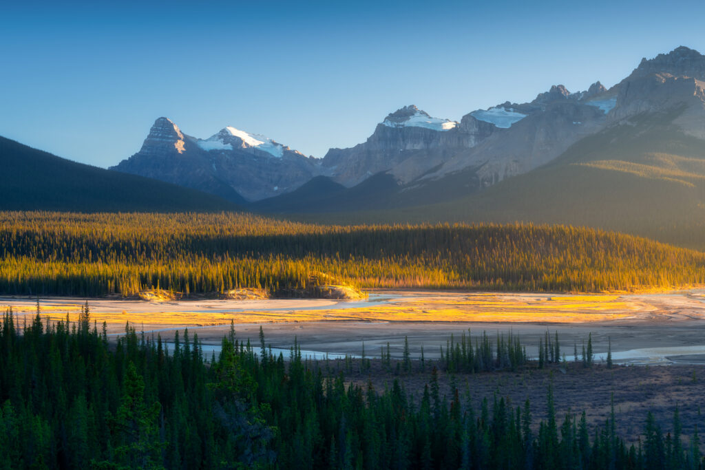 Mountain landscape at dawn. Sunbeams in a valley. High rocky mountains. Alberta, Canada.